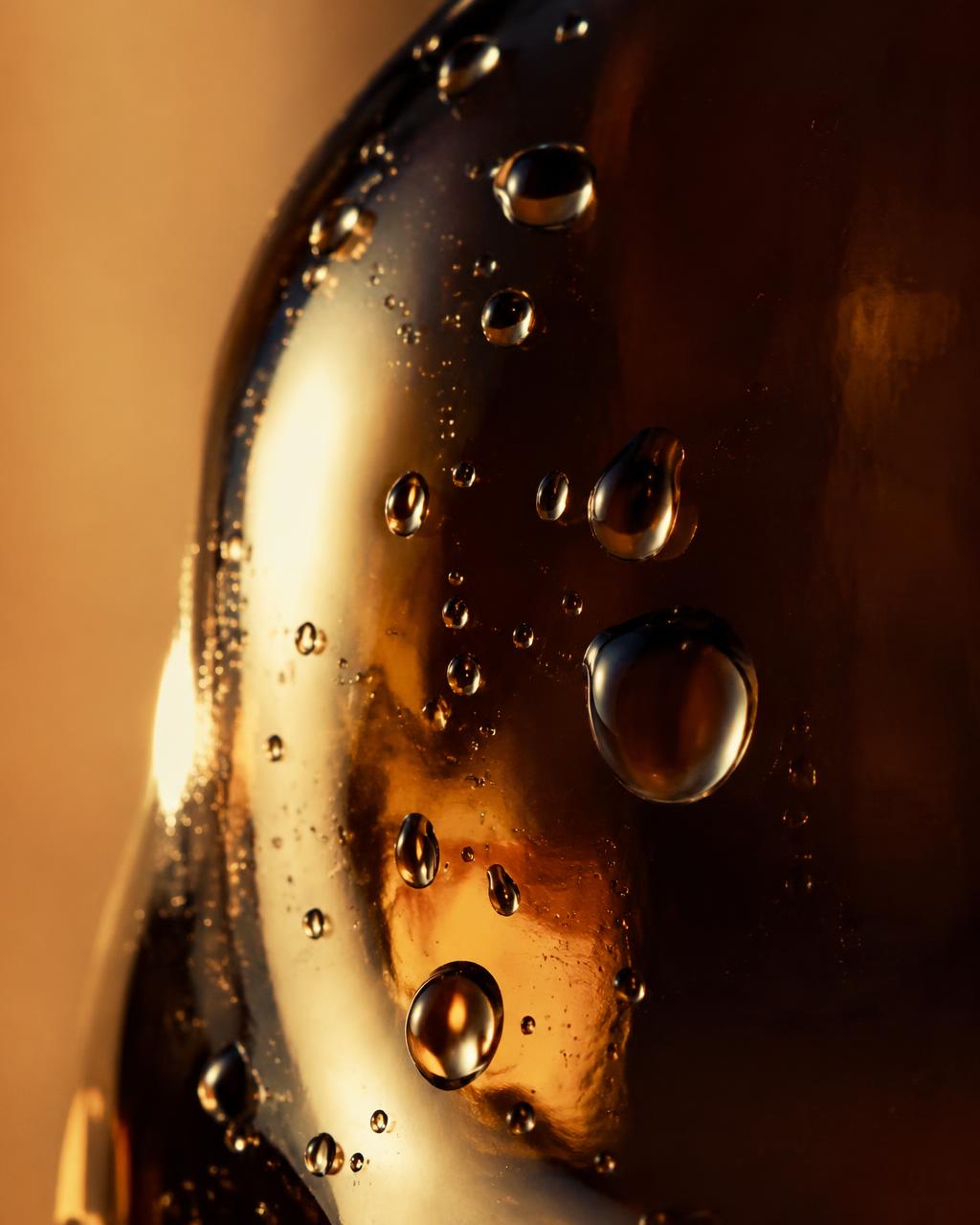 Clear droplets on glass in warm morning light — editorial material study